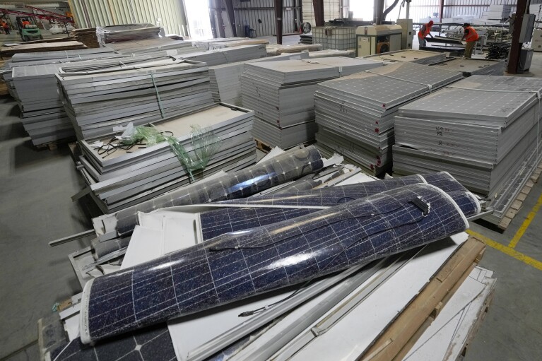 Workers take apart solar panels as they begin the recycling process at We Recycle Solar on Tuesday, June 6, 2023, in Yuma, Ariz. (AP Photo/Gregory Bull)