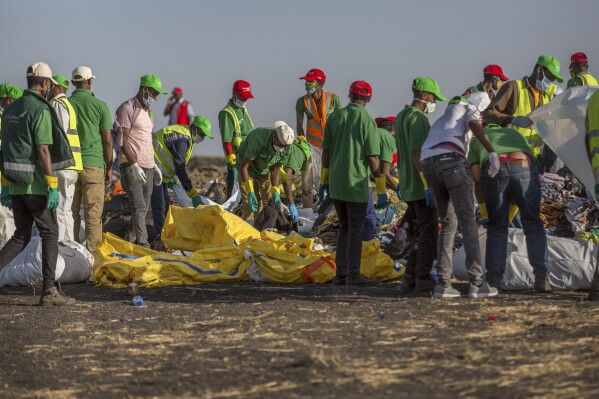 FILE - Workers collect debris on March 12, 2019 at the scene where an Ethiopian Airlines Boeing 737 Max 8 crashed shortly after takeoff, killing all 157 on board, near Bishoftu, or Debre Zeit, south of Addis Ababa, in Ethiopia. (AP Photo/Mulugeta Ayene, File)