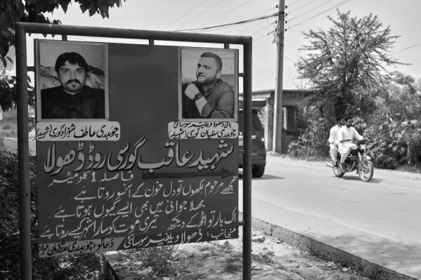 Vehicles pass a billboard featuring two victims who died in a migrant boat journey, along a road in Jaura, a village in Gujrat district, Pakistan, April 16, 2025. (AP Photo/Anjum Naveed)