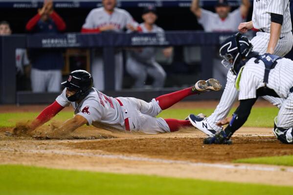 Boston Red Sox's Xander Bogaerts, left, slides past New York Yankees catcher Kyle Higashioka to score on a wild pitch by relief pitcher Michael King during the 11th inning of a baseball game Friday, July 15, 2022, in New York. (AP Photo/Frank Franklin II)