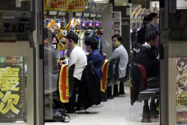 In this April 24, 2020, photo, patrons play at a pachinko gaming parlor in Tokyo. Under Japan's coronavirus state of emergency, people have been asked to stay home. Many are not. Some still have to commute to their jobs despite risks of infection, while others are dining out, picnicking in parks and crowding into grocery stores with scant regard for social distancing. (AP Photo/Kiichiro Sato)