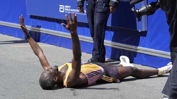 Sisay Lemma, of Ethiopia, celebrates while lying down after winning the Boston Marathon, Monday, April 15, 2024, in Boston. (AP Photo/Steven Senne)