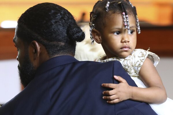 Memory, the 2-year-old daughter of Tomika Miller and Rayshard Brooks, takes in the scene of his coffin while being carried by a funeral home worker during the family processional at Brooks' funeral at Ebenezer Baptist Church, Tuesday, June 23, 2020, in Atlanta. Brooks is to be remembered at the Atlanta church where the Rev. Martin Luther King Jr. once preached. Brooks, 27, was shot twice in the back June 12 by Officer Garrett Rolfe after a struggle that erupted when police tried to handcuff him for being intoxicated behind the wheel of his car at a Wendy's drive-thru. Video showed Brooks snatching a police Taser and firing it at Brooks while running away. (Curtis Compton/Atlanta Journal-Constitution via AP, Pool)