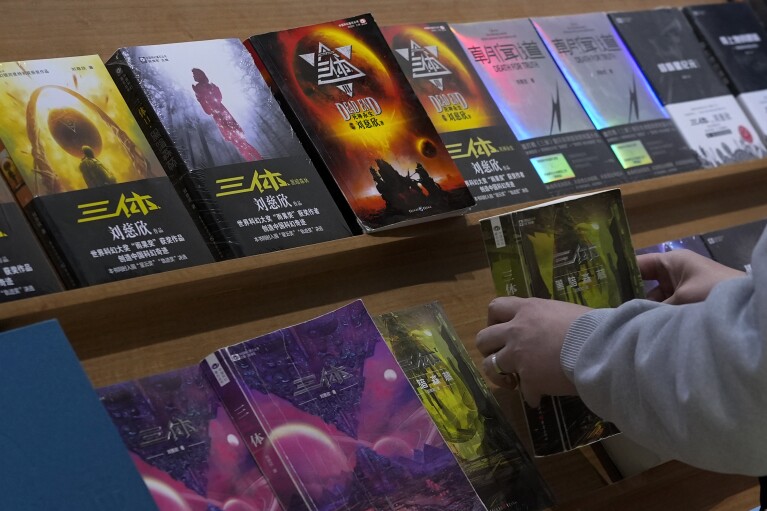 A man looks at copies of "The Three-Body Problem" on display at a bookstore in Beijing on Monday, Feb. 19, 2024. The series, written by former engineer Liu Cixin, helped Chinese science fiction break through internationally, winning awards and making it onto the reading lists of the likes of former U.S. President Barack Obama and Mark Zuckerberg. (AP Photo/Andy Wong)