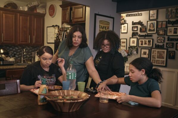 Elena Romero, second from left, and her daughters Gabriela Durham, 17, left, Gionna Durham, 13 second from right, and Grace Durham, 11, have dinner together on Saturday, Jan. 27, 2024, in New York. With the damaging consequences of social media increasingly well documented, many parents are trying to raise their children with restrictions or blanket bans. Teenagers themselves are aware that too much social media is bad for them, and some are initiating social media “cleanses” because of the toll it takes on mental health and grades. (AP Photo/Andres Kudacki)