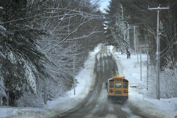 A school bus travels down a slushy-covered road as school resumes following a winter storm, Wednesday, March 15, 2023, in Poland, Maine. The storm dumped heavy, wet snow on parts of the Northeast, causing tens of thousands of power outages. (AP Photo/Robert F. Bukaty)