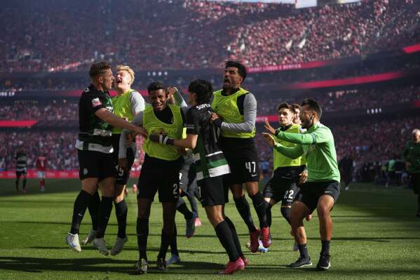 Sporting's Francisco Trincao, center, is congratulated after scoring his side's opening goal during a Portuguese league soccer match between SL Benfica and Sporting CP at the Luz stadium in Lisbon, Saturday, May 10, 2025. (AP Photo/Armando Franca)