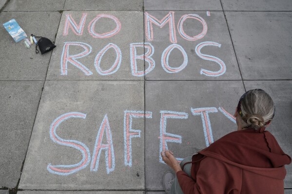 Martha Hubert writes a message opposing a proposed robotaxi expansion on Thursday, Aug. 10, 2023, in San Francisco. (AP Photo/Godofredo A. Vásquez)