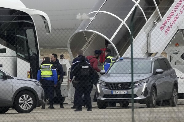 Men board a plane that is stopped by police at Vatry Airport in Vatry, eastern France, on Monday, December 25, 2023.  (AP Photo/Christoph Ena)