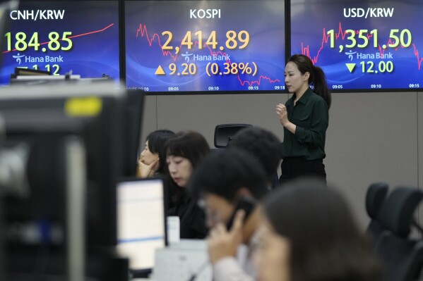 A currency trader passes by the screens showing the Korea Composite Stock Price Index (KOSPI), center, and the foreign exchange rate between the U.S. dollar and South Korean won, right, at the foreign exchange dealing room of the KEB Hana Bank headquarters in Seoul, South Korea, Thursday, Oct. 5, 2023. Asian shares mostly rose Thursday, boosted by a cheaper yen that's a plus for exporting economies in the region, although it recovered slightly in Asian trading. (AP Photo/Ahn Young-joon)