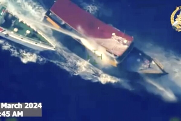 In this screen grab from video provided by the Armed Forces of the Philippines, a Chinese coast guard ship uses water cannons and closely maneuvers beside a Philippine resupply vessel Unaizah May 4 as it approaches Second Thomas Shoal, locally called Ayungin shoal, at the disputed South China Sea on Saturday, March 23, 2024. (Armed Forces of the Philippines via AP)