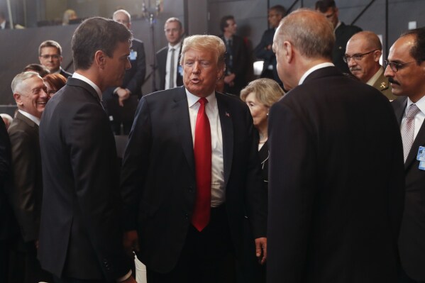 FILE- President Donald Trump, center, stops to talk with Spanish Prime Minister Pedro Sanchez, left, and Turkey's President Recep Tayyip Erdogan, right, as they attend a meeting of the North Atlantic Council during a summit of heads of state and government at NATO headquarters in Brussels on July 11, 2018. (AP Photo/Pablo Martinez Monsivais, Pool, File)