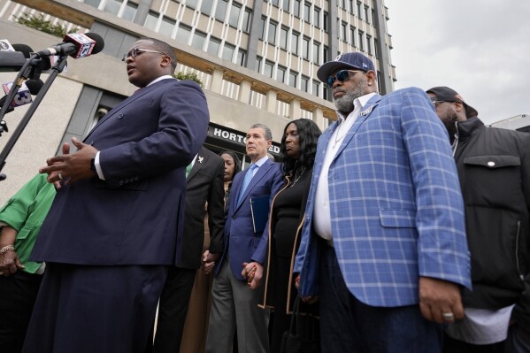 Rev. J. Lawrence Turner, left, leads a prayer vigil with the mother and stepfather of Tyre Nichols, RowVaughn Wells, second from right, and Rodney Wells, right, outside the federal courthouse during the trial of three former Memphis police officers accused of killing her son Wednesday, Sept. 25, 2024, in Memphis, Tenn. (AP Photo/George Walker IV)