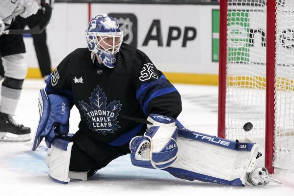 A fan wearing a dinosaur costume sits in the stands as Los Angeles Kings  left wing Kevin Fiala skates by during the second period of an NHL hockey  game against the Toronto