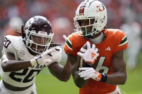 Miami Hurricanes wide receiver Isaiah Horton (16) runs to score a touchdown as Texas A&M Aggies defensive back Jardin Gilbert (20) defends during the first half of an NCAA college football game, Saturday, Sept. 9, 2023, in Miami Gardens, Fla. (AP Photo/Lynne Sladky)