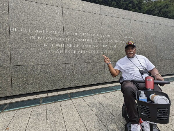 Tommie Babbs, 72, points to a quote on a wall at the Martin Luther King Jr. memorial in Washington on Aug. 11, 2023. Babbs, an academic advisor for the State University of New York at Buffalo who served more than three decades in the military, believes progress has been made toward achieving the dream that the Rev. Dr. Martin Luther King Jr. envisioned on the steps of the memorial nearly 60 years ago at the March on Washington for Jobs and Freedom. (AP Photo/Nathan Ellgren)
