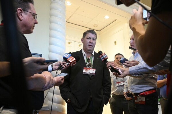 Tampa Bay Buccaneers general manager Jason Licht, center, talks with reporters at the NFL owners meetings, Tuesday, March 26, 2024, in Orlando, Fla. (AP Photo/Phelan M. Ebenhack)