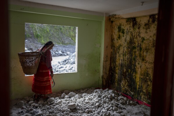 Sita Pandit, 50, walks in her house at Chanaute Market, Melamchi, northeast of Kathmandu, Nepal on Sunday, Sept. 15, 2024, that was damaged by floods in 2021. (AP Photo/Niranjan Shrestha)