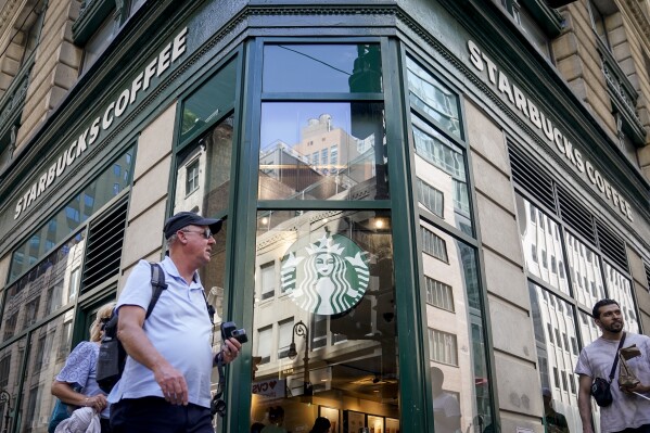 Pedestrians pass a Starbucks in the Financial District of Lower Manhattan, Tuesday, June 13, 2023, in New York. Starbucks is denying union organizers' claims that it banned LGBTQ+ Pride displays in its U.S. stores after Target and other brands experienced backlash. The Seattle coffee giant says there has been no change to its policy and it encourages store leaders to celebrate Pride in June. (AP Photo/John Minchillo)