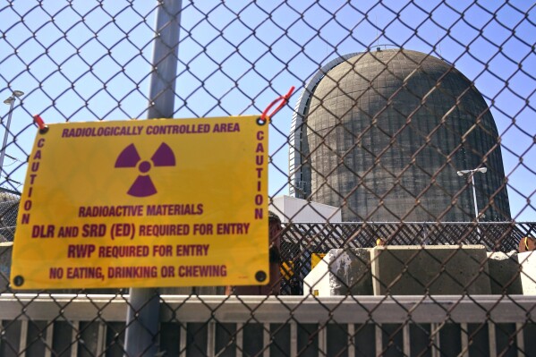 FILE - A sign warning of radioactive materials is seen on a fence around a nuclear reactor containment building, April 26, 2021, a few days before it stopped generating electricity at Indian Point Energy Center, in Buchanan, N.Y. A measure to block radiological discharges into the Hudson River as part of the Indian Point nuclear plant's decommissioning was signed by New York Gov. Kathy Hochul, Friday, Aug. 18, 2023. (AP Photo/Seth Wenig, File)