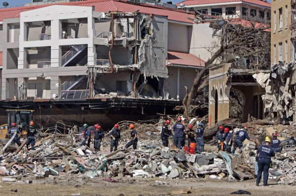 Firefighters from the Los Angeles Fire Department search through the rubble of buildings damaged by Hurricane Katrina along the coastline in East Biloxi, Miss., Sept. 7, 2005. (AP Photo/Darron Cumming, File)