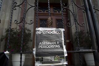 FILE - In this March 11, 2015 file photo, a copy of the front page of the newspaper EL PERIODICO de Guatemala, that reads in Spanish "Journalists killed" hangs on a main gate of the Presidential House during a protest demanding an investigation into the killing of two journalists and increased security for the profession in Guatemala City. A judge in Guatemala has ordered on Tuesday, Feb. 28, 2023, that 9 local journalists of EL PERIODICO newspaper be investigated after the prosecutor’s office complained that recent publications against the judicial system could be considered a crime. (AP Photo/Moises Castillo, File)