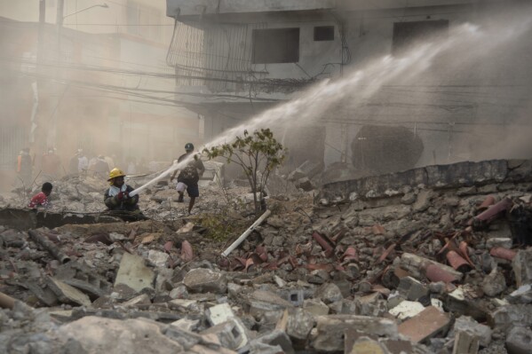 Firefighters put out a fire after a powerful explosion in San Cristobal, Dominican Republic, Monday, Aug 14, 2023. The Monday afternoon explosion killed at least three people and injured more than 30 others, authorities said. (Jolivel Brito/Diario Libre via AP)