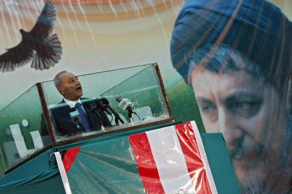 FILE - Lebanese Parliament Speaker Nabih Berri delivers a speech in the southern suburbs of Beirut, Lebanon, Monday, Aug. 31, 2009, Shiite Muslim spiritual leader, Imam Moussa Sadr, seen in the picture right, who disappeared on a trip to Libya in 1978. A delegation of Libyan justice officials in Beirut has reopened discussions with Lebanese officials over the fate of a prominent Lebanese cleric who went missing in Libya decades ago and the potential release of late dictator Moammar Gadhafi’s son, who has held without charges in Lebanon since 2015, according to Lebanese officials. (AP Photo/Bilal Hussein, File)