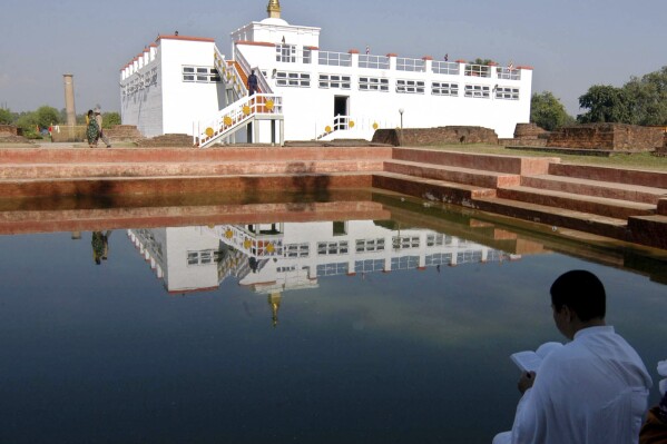 FILE- Sayamongkhoun Alexandera, right, a Buddhist monk from France, prays in front of the birthplace of Lord Buddha, in Lumbini, about 290 kilometers (175 miles) southwest of Katmandu, Nepal, Nov. 30, 2004. The United Nations' cultural agency decided Thursday against putting the Buddhist pilgrimage destination of Lumbini on its list of heritage sites in danger, instead giving authorities in Nepal more time to help restore the famous gardens and temple that are falling into disrepair. (ĢӰԺ Photo/Binod Joshi, File)