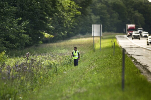 Lansing Police Detective Pete Scheccia, right, and another LPD member search an area along eastbound Interstate 96 near the Williamston Road exit, between Lansing and Detroit, Mich., Wednesday, July 5, 2023, looking for two-year-old Wynter Cole Smith, who went Sunday, July 2. (Matthew Dae Smith/Lansing State Journal via AP)