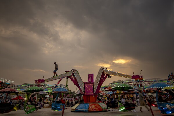 A man checks a ride arm at a fair in Hagioaica, Romania, Saturday, Sept. 16, 2023. For many families in poorer areas of the country, Romania's autumn fairs, like the Titu Fair, are one of the very few still affordable entertainment events of the year. (AP Photo/Andreea Alexandru)