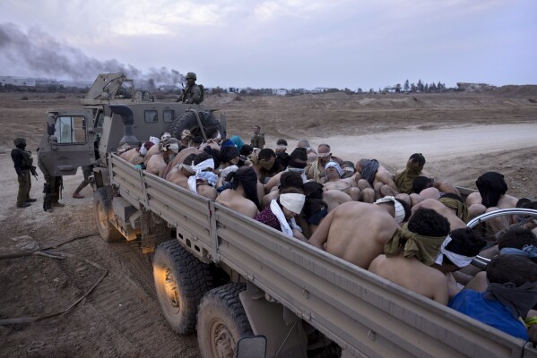 Israeli soldiers stand by a truck packed with bound and blindfolded Palestinian detainees in Gaza, Friday, Dec. 8, 2023. Israeli forces have been rounding up Palestinians in northern Gaza for interrogation as they search for Hamas fighters. (AP Photo/Moti Milrod, Haaretz)