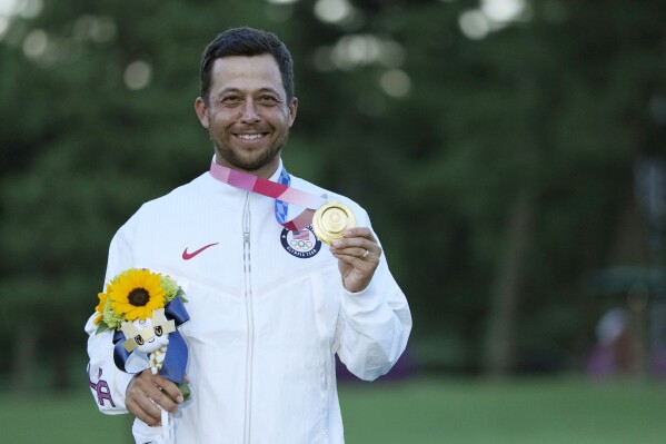 Xander Schauffele, of the United States, holds his gold medal in the men's golf at the 2020 Summer Olympics on Sunday, Aug. 1, 2021, in Kawagoe, Japan. Eleven players from the Tokyo Games are now with LIV Golf and will have a hard time making it back to the Olympics. (AP Photo/Andy Wong)