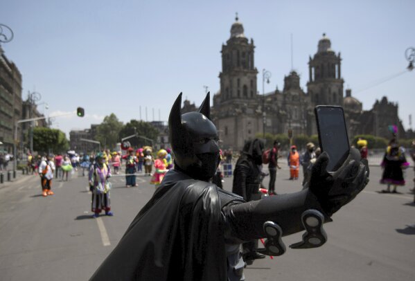 A street performer dressed as Batman takes a selfie during a protest in Mexico City, Thursday, April 30, 2020. The city's street performers marched to Mexico City’s main square the Zocalo, protesting in front of the national palace against restrictions designed to help stop the spread of COVID-19 disease, barring them from working on the streets. (AP Photo/Fernando Llano)