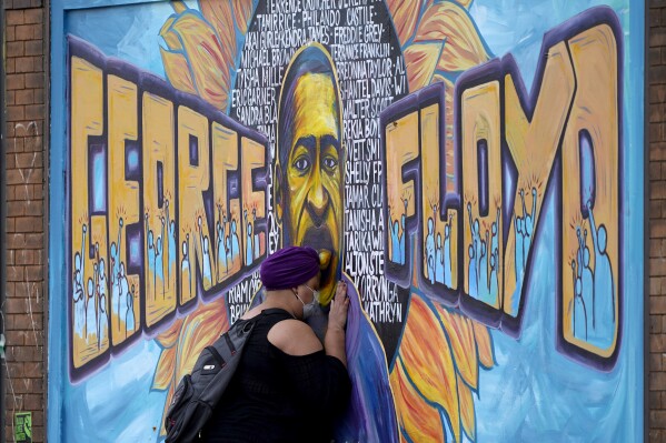 FILE - Damarra Atkins pays respect to George Floyd at a mural at George Floyd Square, Friday, April 23, 2021, in Minneapolis. In a new study, Black Americans expressed broad concerns about how they are depicted in the news media, with majorities saying they see racist or negative depictions and a lack of effort to cover broad segments of their community. (AP Photo/Julio Cortez, File)