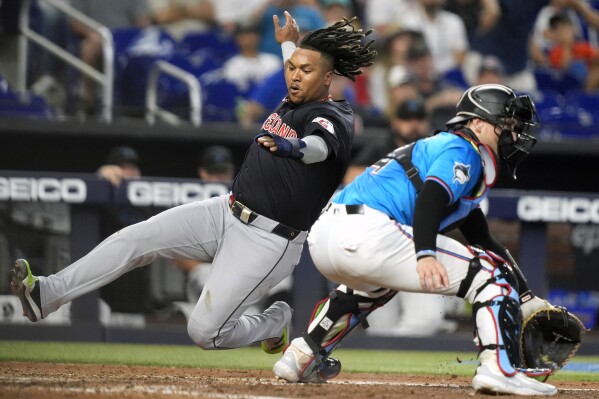 Cleveland Guardians' Jose Ramirez, left, scores past Miami Marlins catcher Nick Fortes, right, on a single hit by David Fry during the sixth inning of a baseball game Sunday, June 9, 2024, in Miami. (AP Photo/Lynne Sladky)