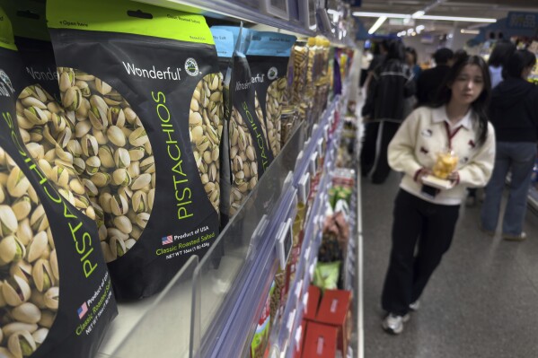 People walk by shelf displaying imported nuts from the United States, at the Hema supermarket, in Beijing, Tuesday, April 8, 2025. (AP Photo/Andy Wong)