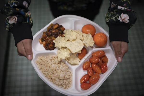 CORRECTS DAY/DATE TO FRIDAY, FEB. 10, 2023 INSTEAD OF SATURDAY, FEB. 11 - A seventh grader carries her plate which consists of three bean chili, rice, mandarins and cherry tomatoes and baked chips during her lunch break at a local public school, Friday, Feb. 10, 2023, in the Brooklyn borough of New York. A 2010 federal law that boosted nutrition standards for school meals may have helped curb obesity among America’s children _ even teenagers who can buy their own snacks, according to a study published Monday, Feb. 13, 2023, in the journal JAMA Pediatrics. (AP Photo/Wong Maye-E)
