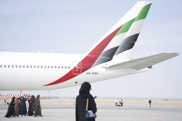 Emirati women walk past the tail of an Emirates Boeing 777 at the Dubai Air Show in Dubai, United Arab Emirates, Wednesday, Nov. 15, 2023. (AP Photo/Jon Gambrell)