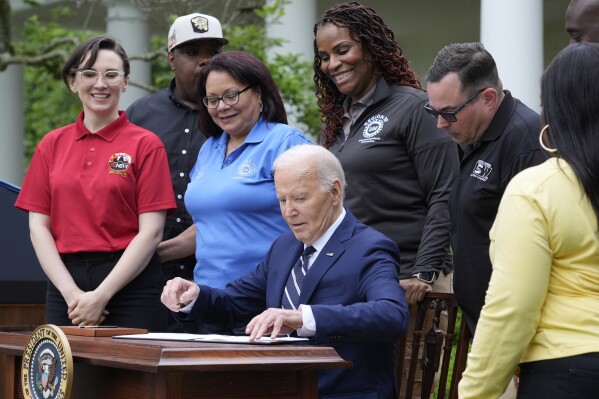 President Joe Biden sits down to sign a document in the Rose Garden of the White House in Washington, Tuesday, May 14, 2024, imposing major new tariffs on electric vehicles, semiconductors, solar equipment and medical supplies imported from China. (AP Photo/Susan Walsh)