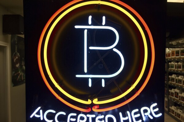 A neon sign that alerts customers that the business accepts bitcoin as payment, hangs in the window of Healthy Harvest Indoor Gardening in Hillsboro, Ore., on Feb. 7, 2018. (AP Photo/Gillian Flaccus, File)