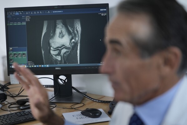 Dr. David Altchek talks about some aspects of Tommy John surgery while showing an x-ray of a patient at his office in New York, Thursday, Feb. 29, 2024. (AP Photo/Seth Wenig)