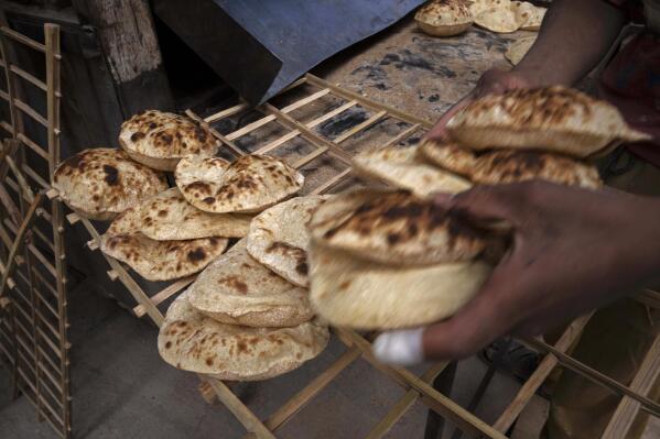 FILE - A worker collects Egyptian traditional 'baladi' flatbread, at a bakery, in el-Sharabia, Shubra district, Cairo, Egypt, Wednesday, March 2, 2022. Ukraine's government banned the export of wheat, oats and other food staples on Wednesday, March 9, 2022 as authorities try to make sure they can feed people while Russia's invasion intensifies.(AP Photo/Nariman El-Mofty, File)