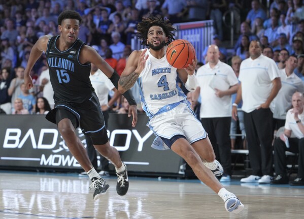 In a photo provided by Bahamas Visual Services, North Carolina's RJ Davis drives to the basket with Villanova's Jordan Longino close behind during overtime in an NCAA college basketball game in the Battle 4 Atlantis at Paradise Island, Bahamas, Thursday, Nov. 23, 2023. (Ronnie Archer/Bahamas Visual Services via AP)