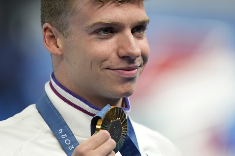 Leon Marchand of France, poses with his gold medal for the men's 200-meter individual medley final at the 2024 Summer Olympics, Friday, Aug. 2, 2024, in Nanterre, France. (AP Photo/Ashley Landis)