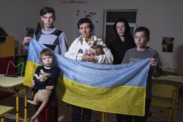 Natalia Zhyvohliad, an internally displaced person from Nova Petrivka in the Zaporizhzhia region of Ukraine, poses with some of her children at the IDP shelter in Kyiv, Friday, Jan. 19, 2024. (AP Photo/Evgeniy Maloletka)