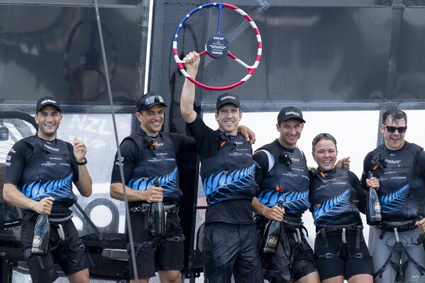 In this photo provided by SailGP, Peter Burling, Co-CEO and driver of New Zealand SailGP Team, lifts the trophy as the team celebrates aboard their F50 catamaran after winning the Mubadala New York Sail Grand Prix in New York, Sunday, June 23, 2024. (Bob Martin/SailGP via AP)