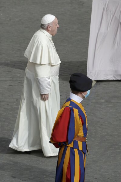 FILE - In this Sept. 2, 2020 file photo, Pope Francis walks by a Vatican Swiss guard wearing a face mask to prevent the spread of COVID-19 as he arrives at the San Damaso courtyard for his general audience, the first with faithful since February when the coronavirus outbreak broke out, at the Vatican. On Monday, Oct. 12, 2020, the Vatican said in a statement  that four Swiss Guards have tested positive for the coronavirus, as the surge in infections in surrounding Italy enters the Vatican walls. (AP Photo/Andrew Medichini, file)