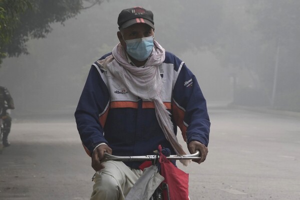 A cyclist wears mask to head to his work-point as smog envelops the areas of Lahore, Pakistan, Wednesday, Nov. 8, 2023. Residents of Lahore and adjacent areas are suffering from respiratory problems because of poor air quality related to thick smog hanging over the region. (AP Photo/K.M. Chaudary)