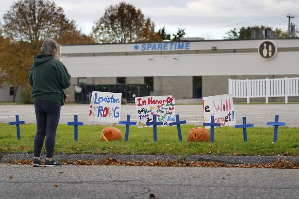FILE - A woman visits a makeshift memorial outside Sparetime Bowling Alley, the site of one of this week's mass shootings, Saturday, Oct. 28, 2023, in Lewiston, Maine. Police in Maine feared confronting Robert Card, an Army reservist in the weeks prior to the worst mass shooting in state history would “throw a stick of dynamite on a pool of gas,” according to footage released by law enforcement, Friday, Dec. 22. (AP Photo/Robert F. Bukaty, File)